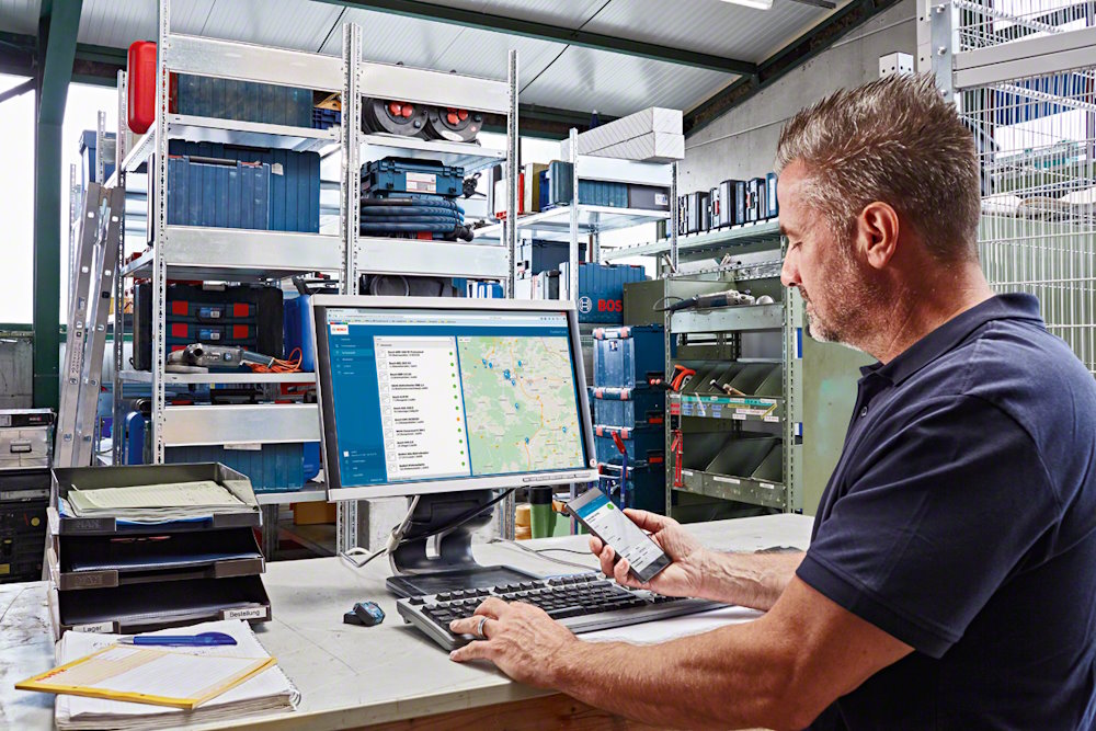 Person am Computer mit Smartphone